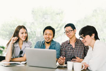 Diverse group of Asian business coworkers or college students using laptop in team casual meeting, startup project discussion or happy teamwork brainstorm concept, at coffee shop or modern office