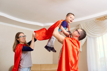 A family dressed in superhero costumes plays  the room.