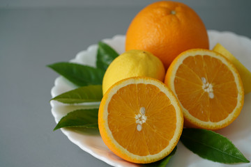 Organic orange and lemon on white plate with the gray background - Isolated