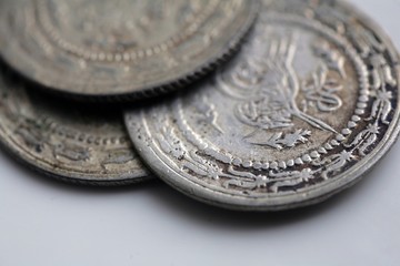 Close up of antique silver coins on white background; old money background.