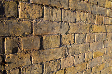 Abstract of section of brown stone wall leading away from the camera with texture from directional sunlight.