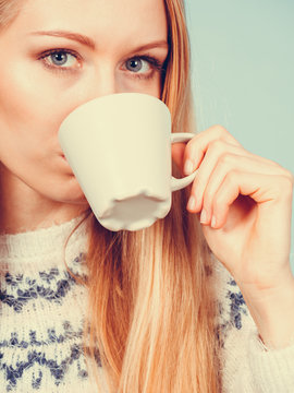Blonde woman drinking hot drink from cup