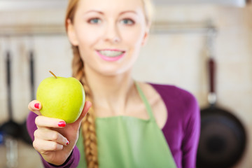 Woman young housewife in kitchen with apple fruit