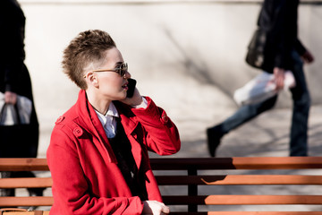 The model sits with a mobile on the bench