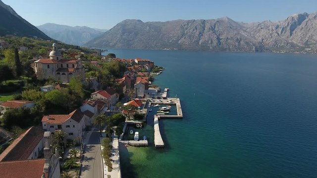 Aerial view of the seashore landscape of Prcanj, Boko-Kotor bay. Buildings of the old town with red roofs, marina with boats