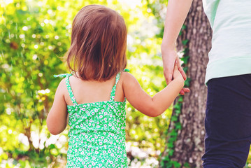 Toddler girl holding hands with her mother