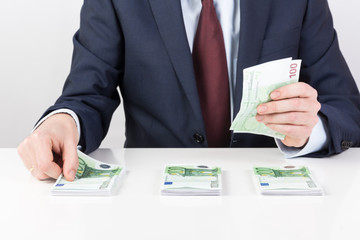 bank teller's hands counting euro banknotes on the table.