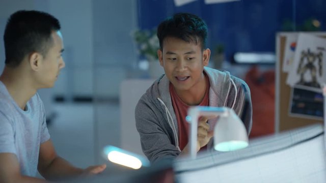  Game designers looking at computer screen & discussing character artwork