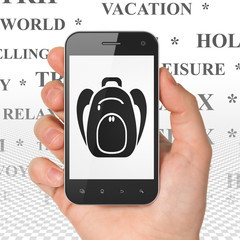 Tourism concept: Hand Holding Smartphone with Backpack on display