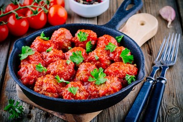 Meatballs with tomato sauce and parsley in cast iron pan