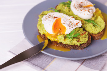 Toast with poached egg, puree avocado, spices and arugula