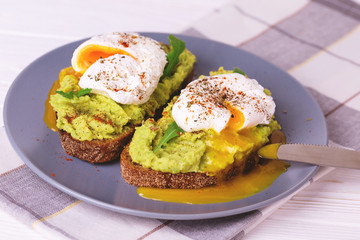 Toast with poached egg, puree avocado, spices and arugula