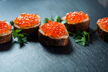 Red caviar on slate background.