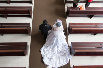 Bride and groom walk in to the church holding their hands together at wedding