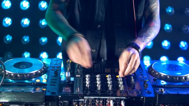 DJ hands tweak track controls on dj's deck. 4K.