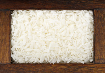 Dried grated coconut in wooden box isolated