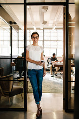 Fototapeta premium Young woman at office doorway holding a coffee