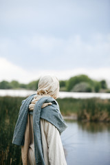 Jesus Christ pondering while standing next to a river, overlooking the setting sun. 