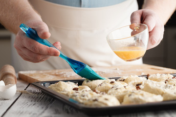 smearing raw buns with brush in yolk, preparation process