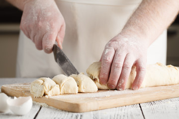 Raw sweet yeast dough on a baking sheet, filling buns raisin. Preparation for baking. The concept of chefs and baking.