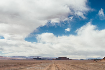 Fototapeta na wymiar Dirt road with Antofagasta and Alumbrera volcanoes background in Catamarca, Argentina