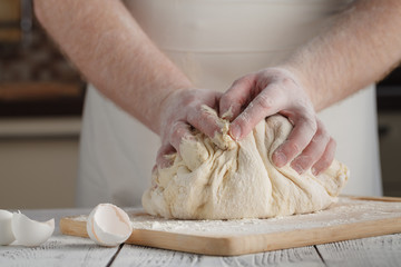 man's hands knead dough on a table