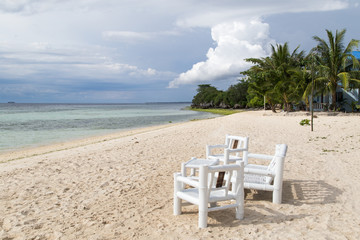 White table and chair on the beach of a sandy beach.