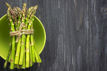 Organic, fresh asparagus in a green bowl. Top view