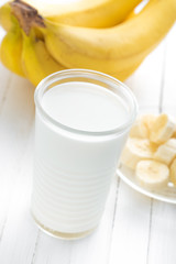 Yogurt with fresh bananas on white wooden background closeup, healthy breakfast