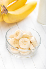 Fresh sliced bananas on white wooden background closeup, healthy eating