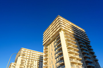 Modern apartment block with balcony against a blue sky.