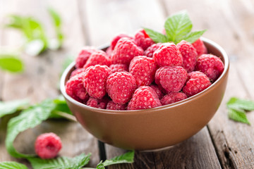 Fresh raspberry with leaves on wooden background