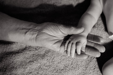 great-grandmother holds the hands of his beloved grandson by the window