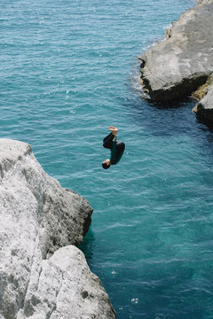 Boy jumping to the sea from the stone
