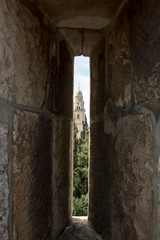 A peek hole in the wall around the old city of Jerusalem with in the background tower of the Abbey of the Dormition