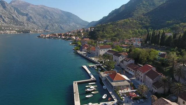 Aerial view of the seashore landscape of Prcanj, Boko-Kotor bay. Buildings of the old town with red roofs, marina with boats
