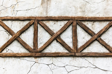 Old stone wall in the cracks with wooden slats.