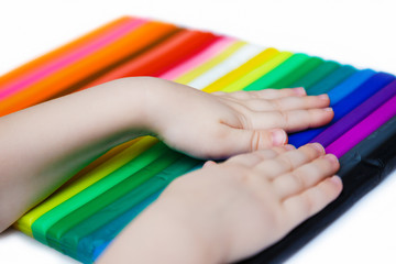 Child hands playing with colorful plasticine. Set of plasticine palettes on white background. Rainbow colors