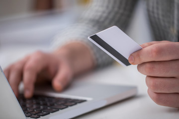 Man holding credit card and using laptop for online shopping in close up