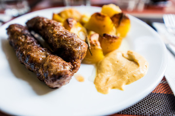 Romanian traditional food Mititei with French fries and mustard on white plate. Romanian dish
