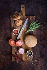 Homemade burger with ingredients on wooden board. View from above, flat lay.