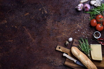 Sandwich cooking ingredients. French baguette with cheese and vegetables over rustic counter top. View above, copy space.