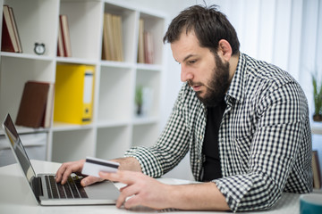 Bearded man in office online shopping with credit card