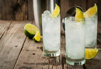 Foto op Plexiglas Alcoholische drank. Wodka en tonic highball cocktail met een limoen garnituur, op een oude houten rustieke tafel. Ruimte kopiëren © ricka_kinamoto