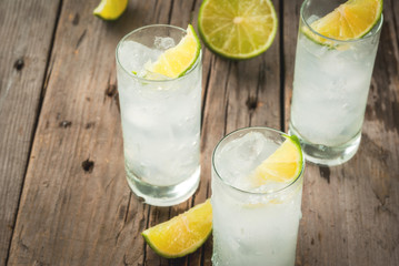 Alcoholic drink. Vodka and tonic highball cocktail with a lime garnish, on an old wooden rustic table. Copy space