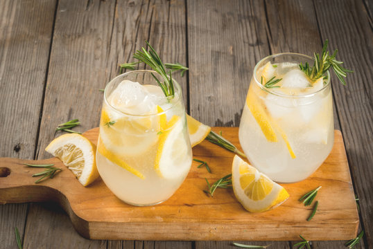 Summer refreshments. Detox water. Lemonade. Tonic with ice, lemon and rosemary, on an old wooden rustic table. Copy space