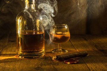 Whisky Glas und Flasche und eine stark qualmende Zigarre 
