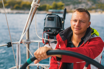 Happy sailor at the helm of his sailing yacht.