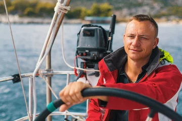 Wall murals Sailing Happy sailor at the helm of his sailing yacht.