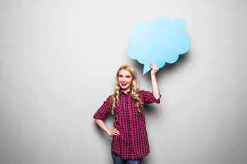 Cheerful attractive young woman standing and holding blank speech bubble over grey background